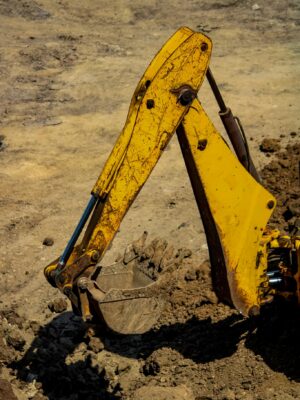 Close-up of a yellow excavator arm working in sandy soil, highlighting heavy machinery function.