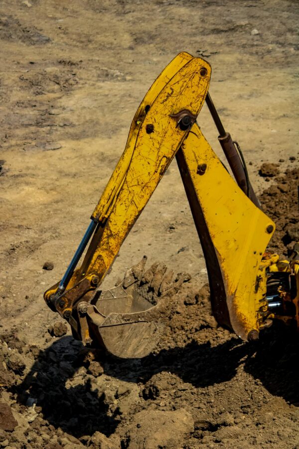 Close-up of a yellow excavator arm working in sandy soil, highlighting heavy machinery function.