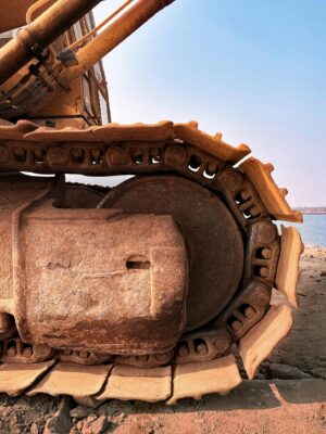 Detailed view of an excavator on sandy terrain by Alappuzha's shore, showcasing engineering strength.