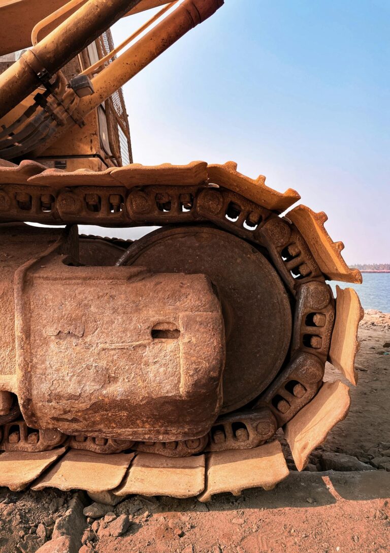 Detailed view of an excavator on sandy terrain by Alappuzha's shore, showcasing engineering strength.