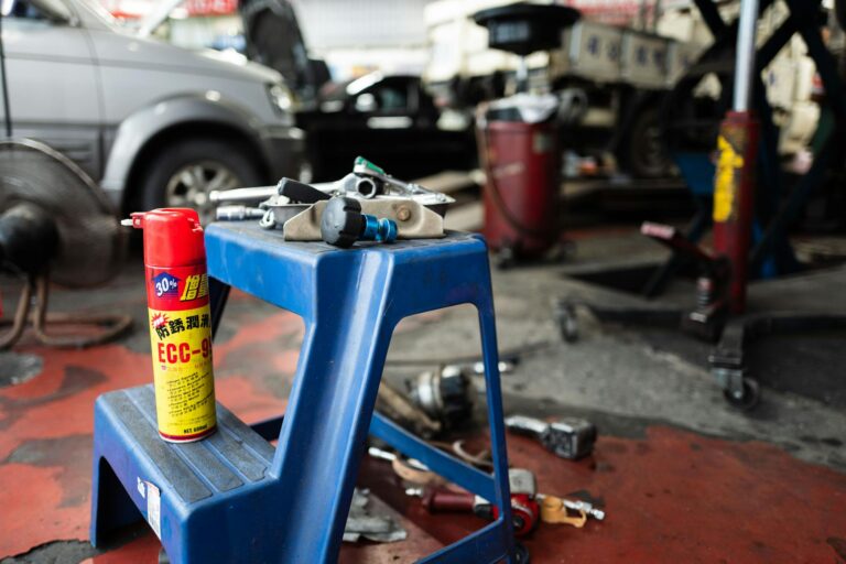 Dynamic view of a workshop with tools and automotive parts on a stool, inside a repair shop.